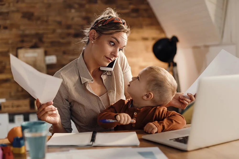 Femme qui travaille difficilement avec enfant sur les genoux